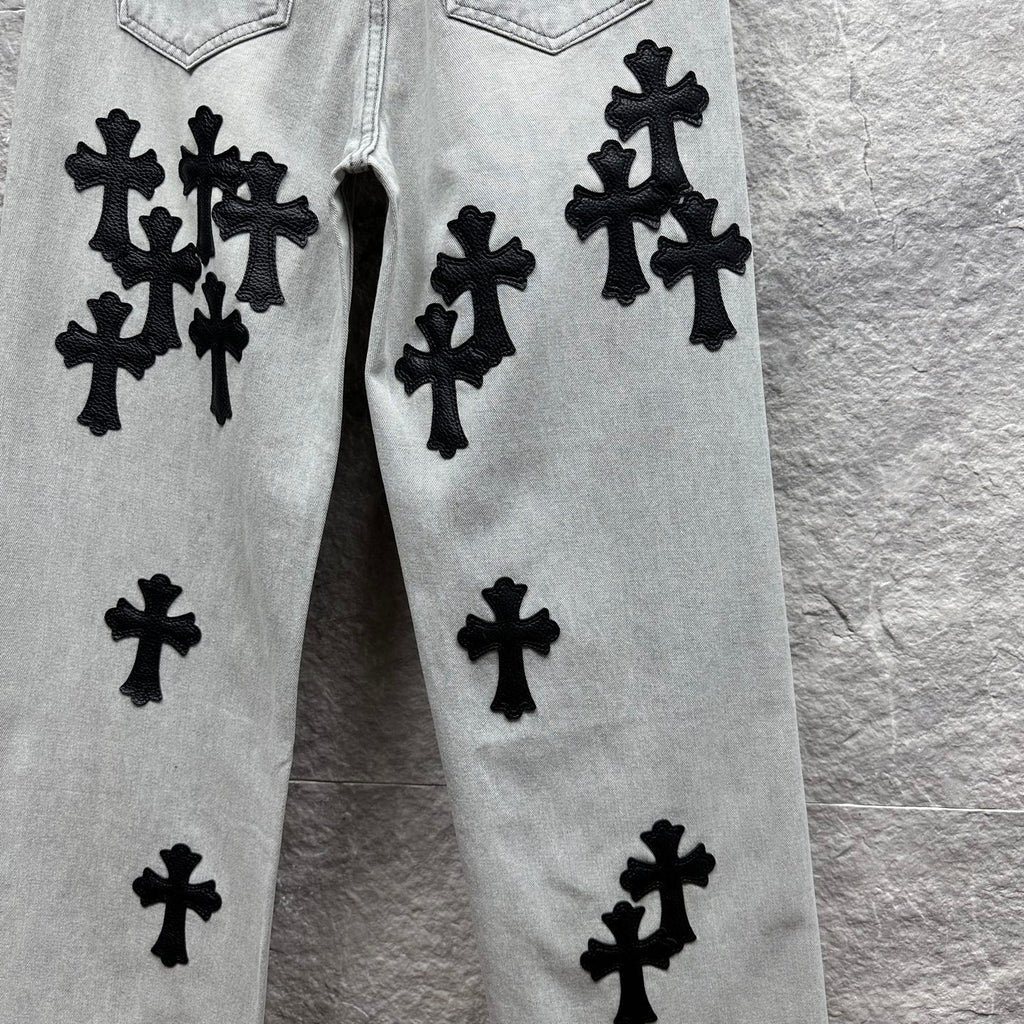 Light wash denim pants with black cross appliqués on front panels