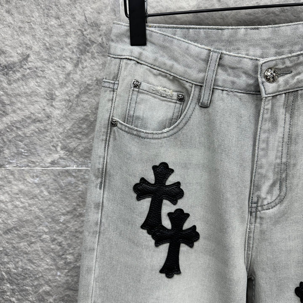 Light wash denim pants front pocket with black cross appliqué near hip