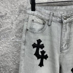 Light wash denim pants front pocket with black cross appliqué near hip