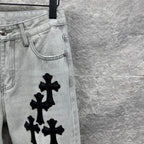 Light wash denim pants with black cross appliqués and curved front yoke