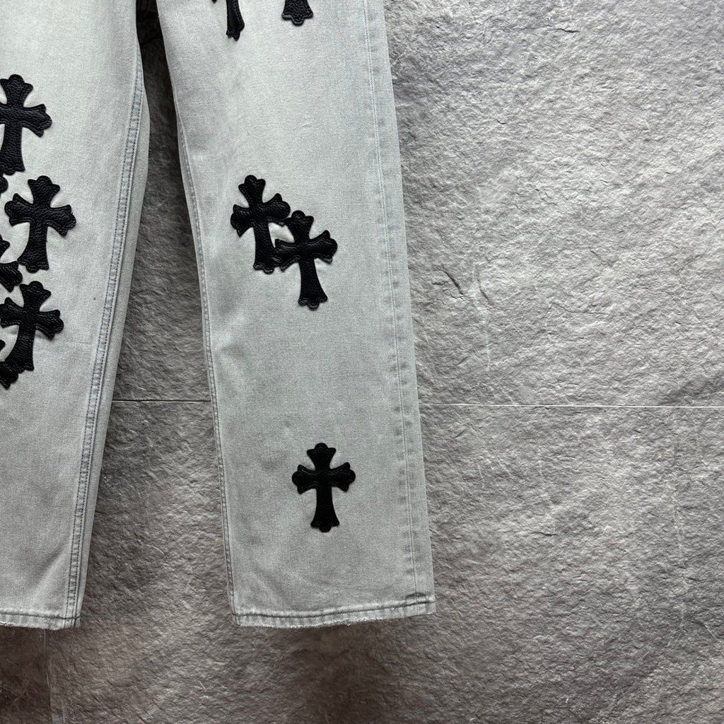 Light wash denim pants leg with scattered black cross appliqués