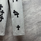 Light wash denim pants leg with scattered black cross appliqués