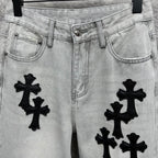 Light wash denim pants with black cross appliqués, front pockets and button closure