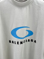 Close-up of white T-shirt chest graphic: blue Balenciaga logo and text