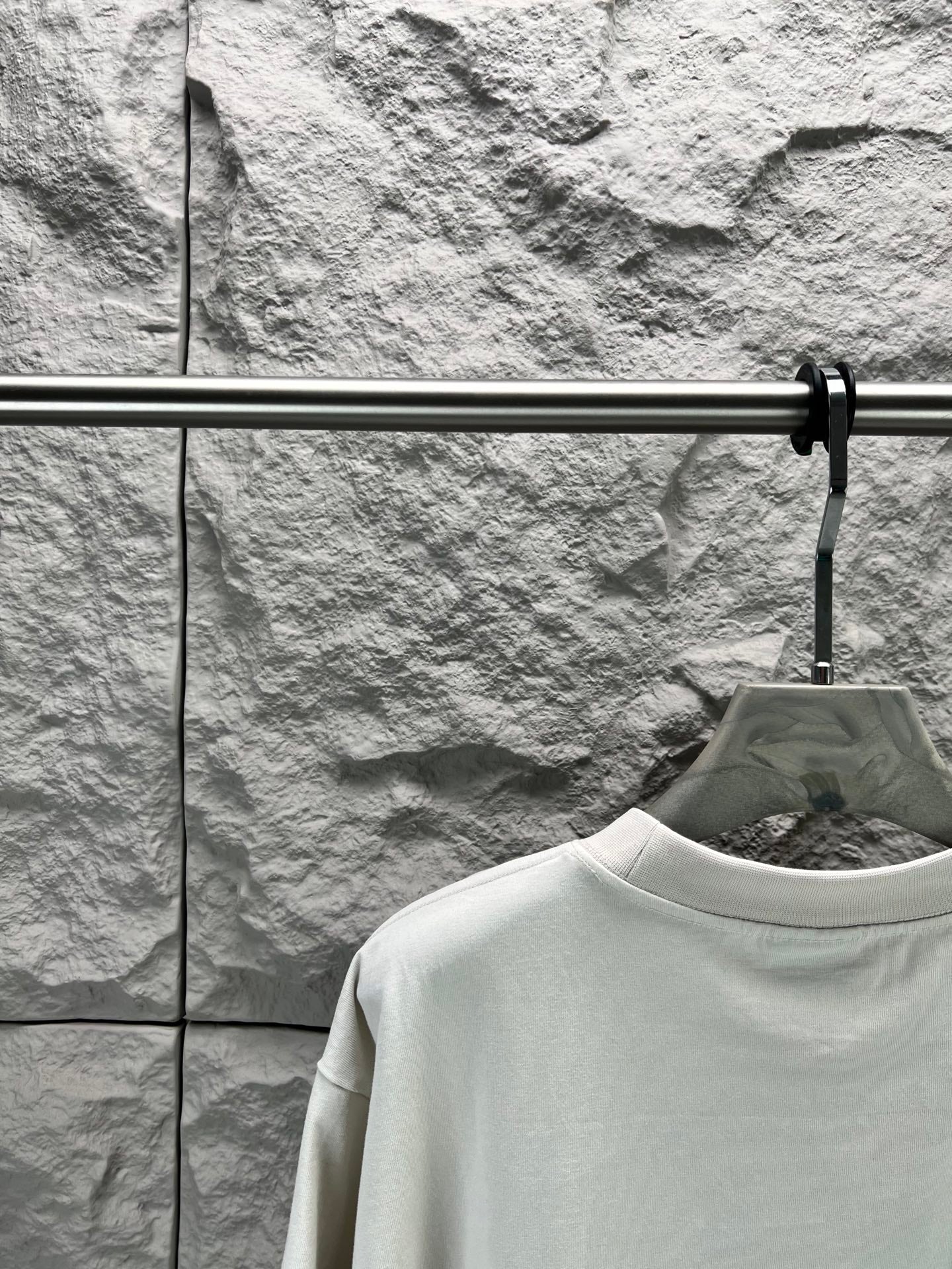 White crew-neck T-shirt neckline detail on a hanger