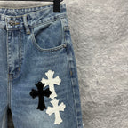Light blue denim pants close-up of back pocket and large cross applique on leg