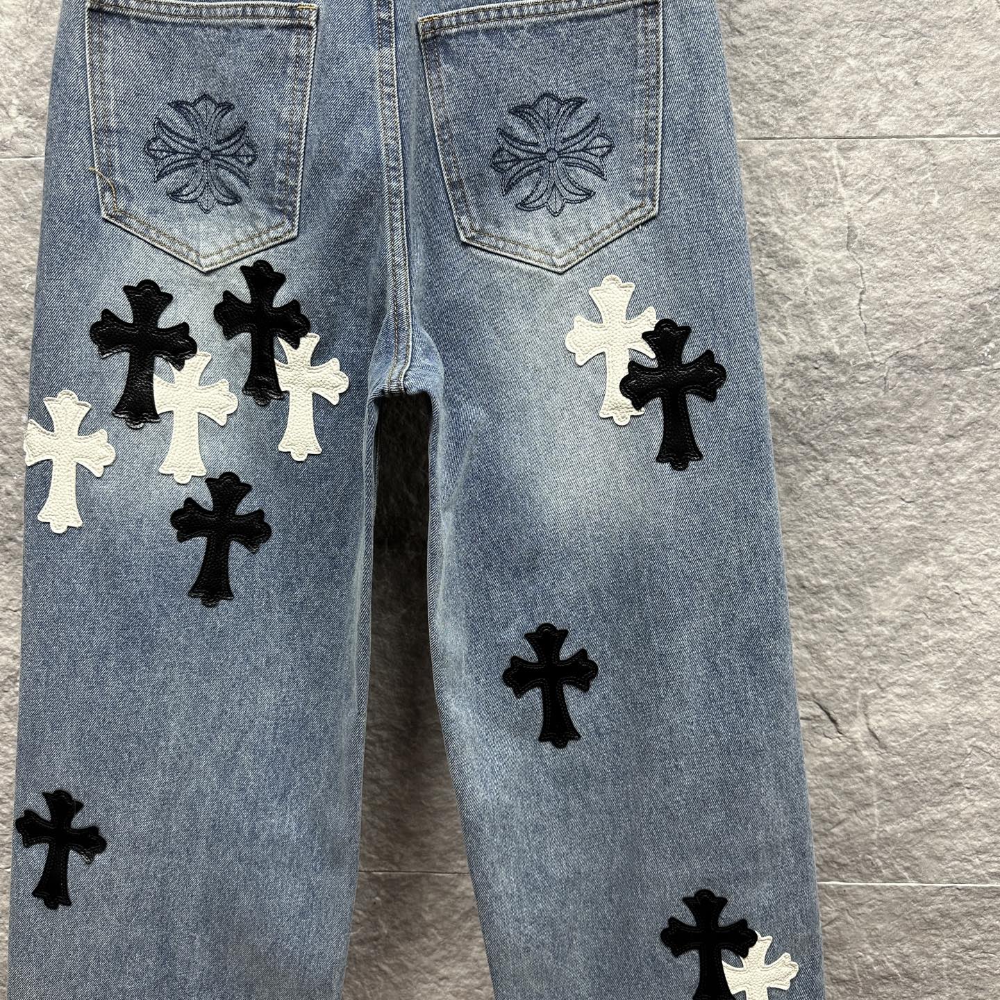 Light blue denim pants back view with pocket embroidery and black and white cross applique