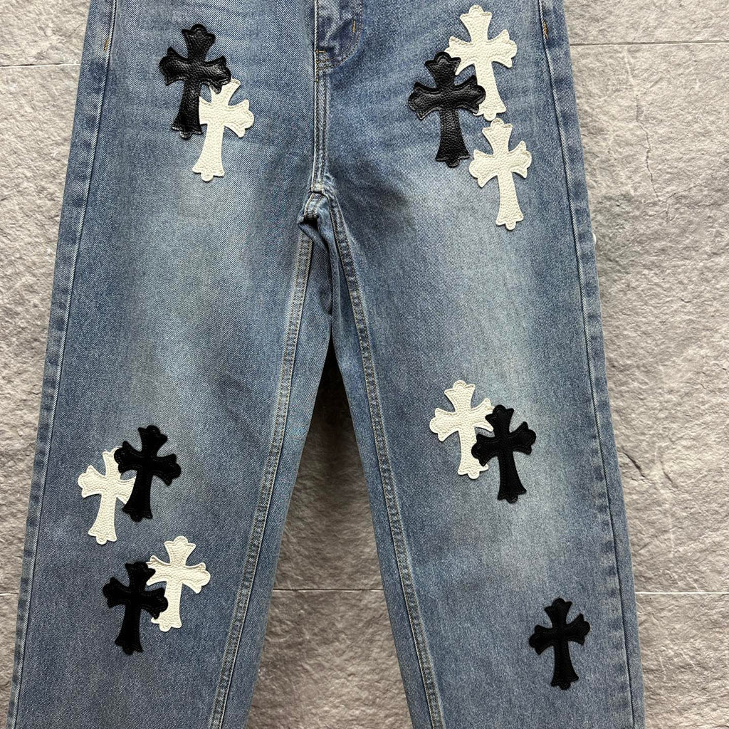 Light blue denim pants front view with black and white cross applique across legs