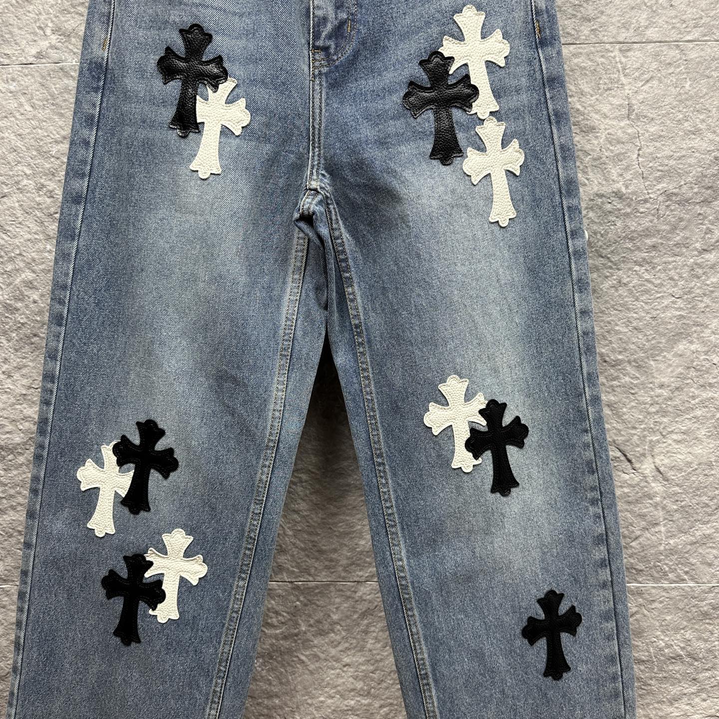 Light blue denim pants front view with black and white cross applique across legs