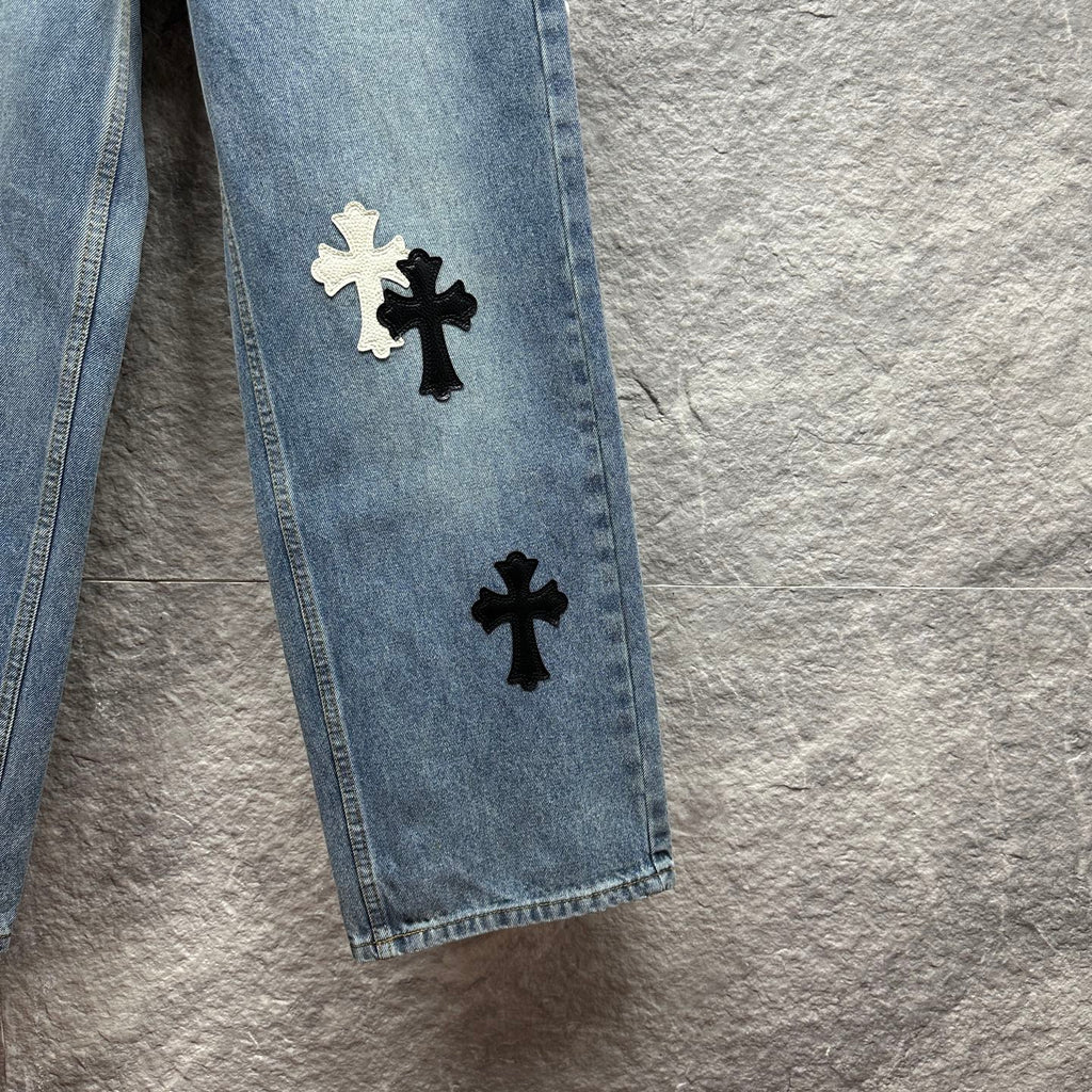 Light blue denim pants leg close-up with stacked black and white cross applique