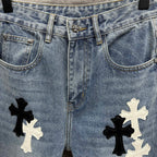 Light blue denim pants close-up: waistband, pockets, and cross applique on both legs