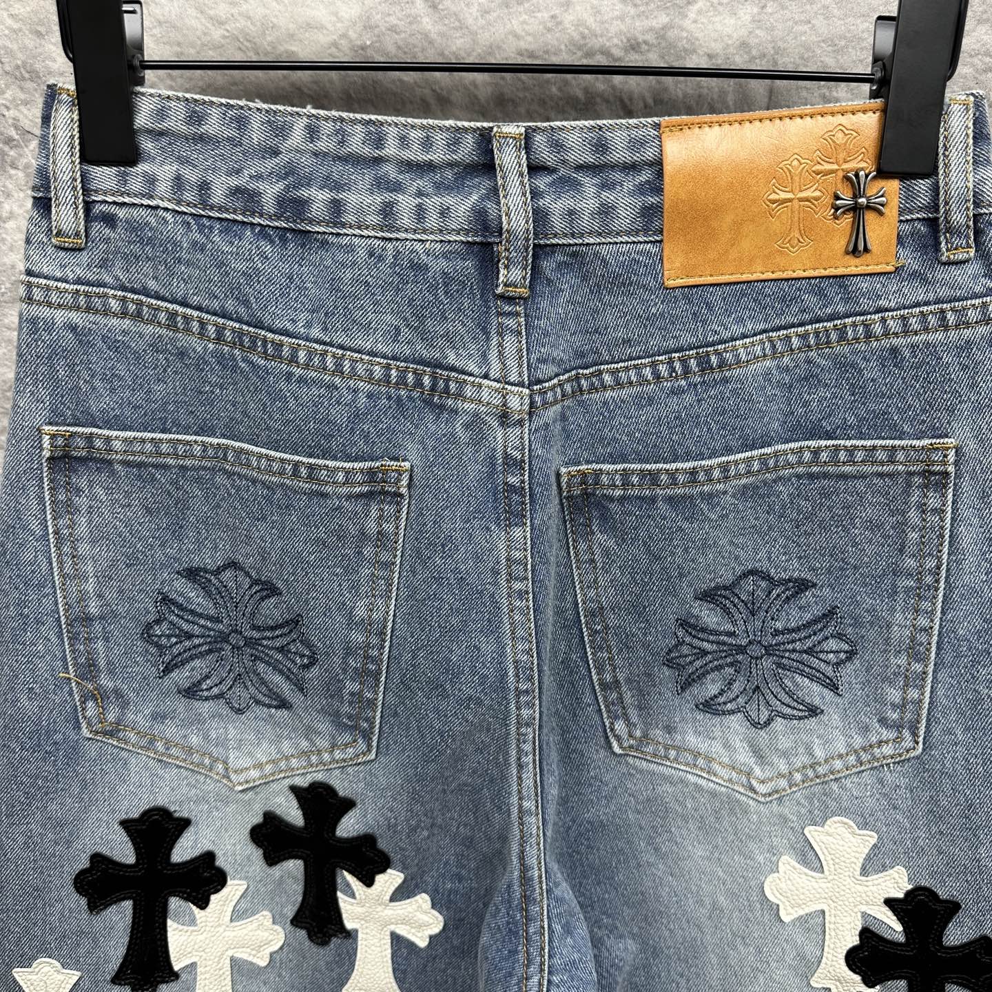 Light blue denim pants close-up: back pockets with embroidered design and cross applique
