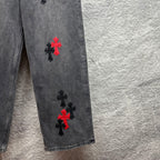 Grey denim pants with red and black cross embroidery on lower leg