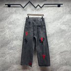 Grey denim pants with cross embroidery in red and black, back view