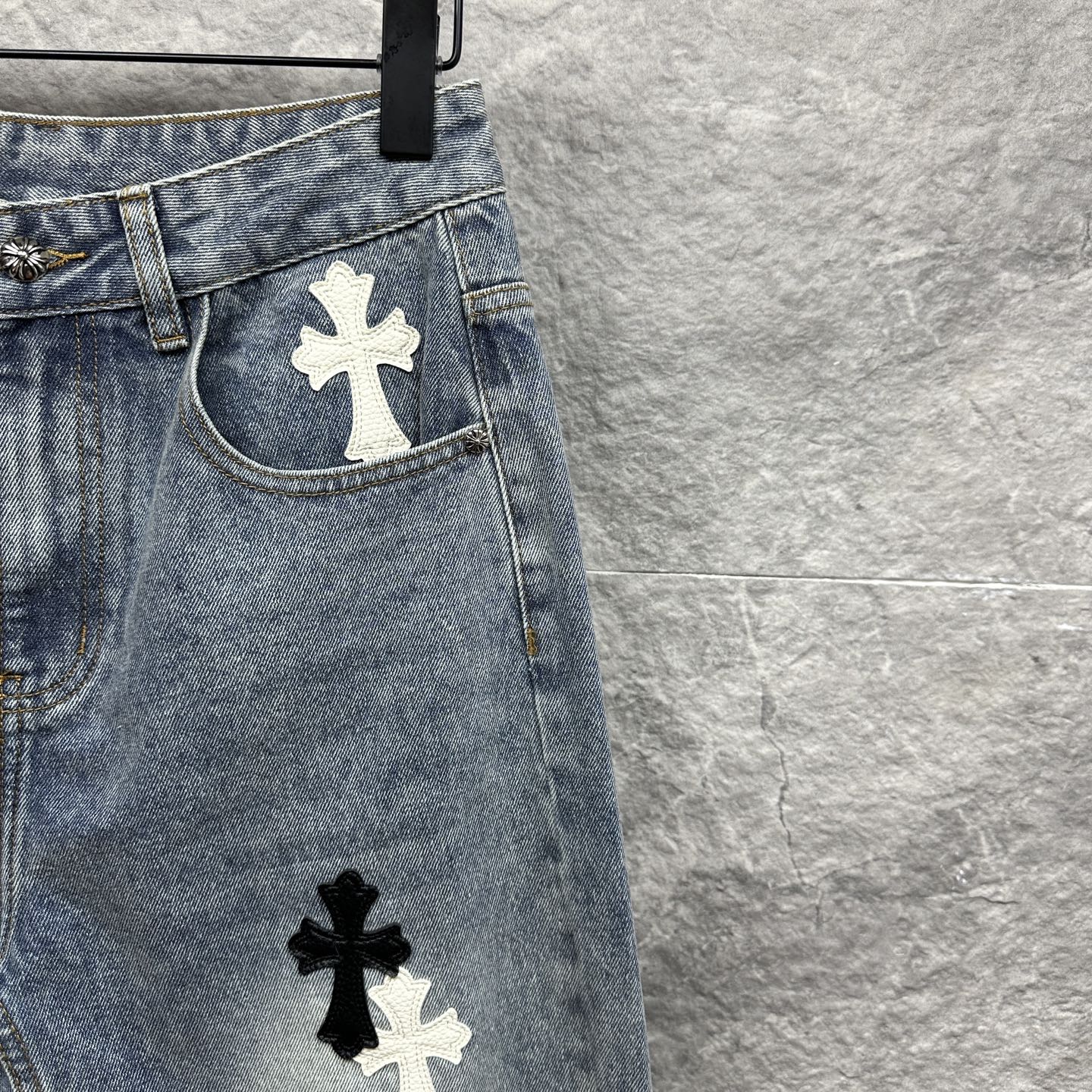 Light-wash denim pants with cross patches near pockets and lower leg