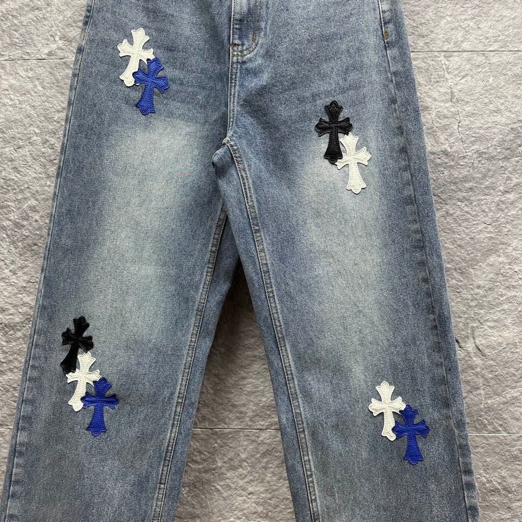 Light-wash denim pants with multiple cross patches on the front, full front view