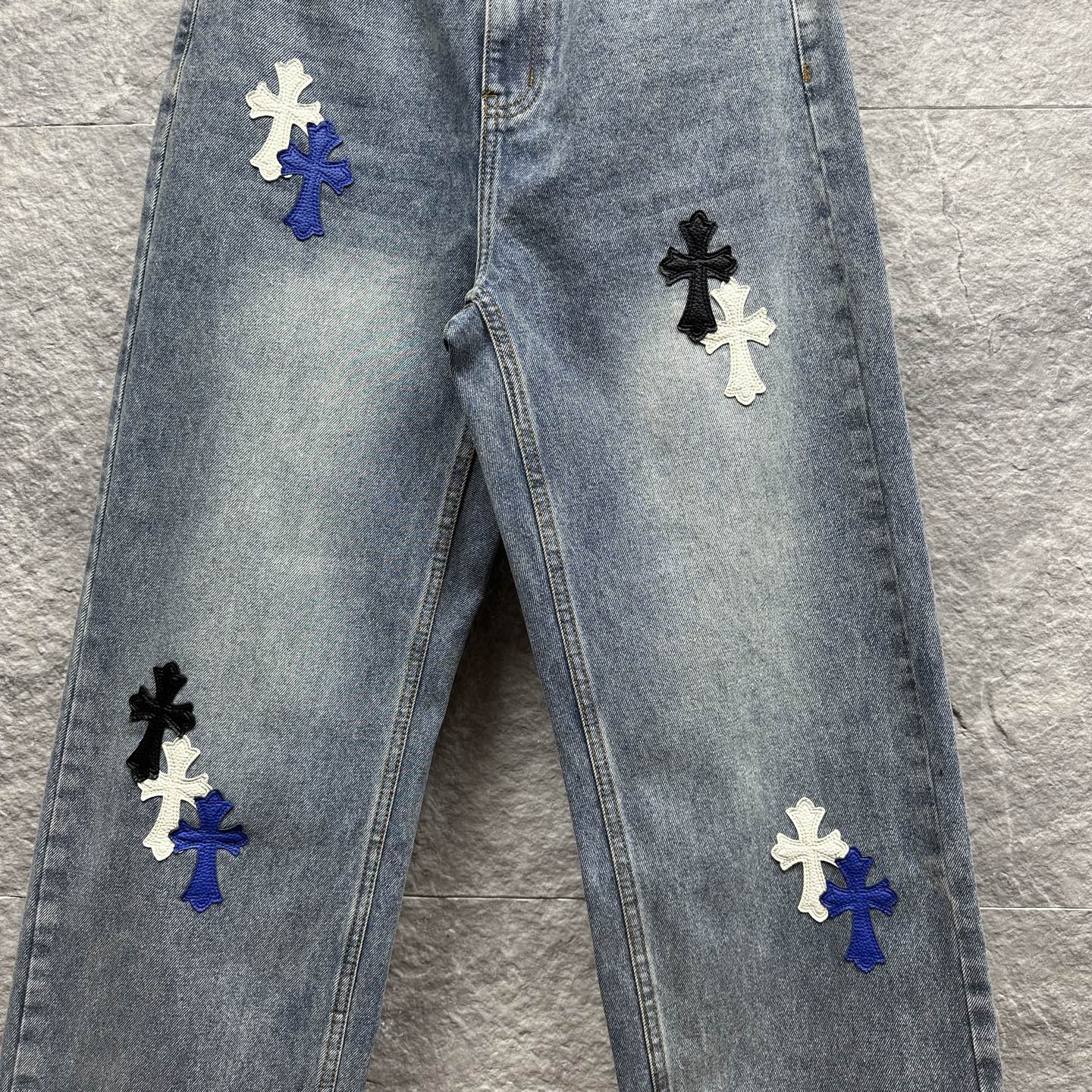 Light-wash denim pants with multiple cross patches on the front, full front view