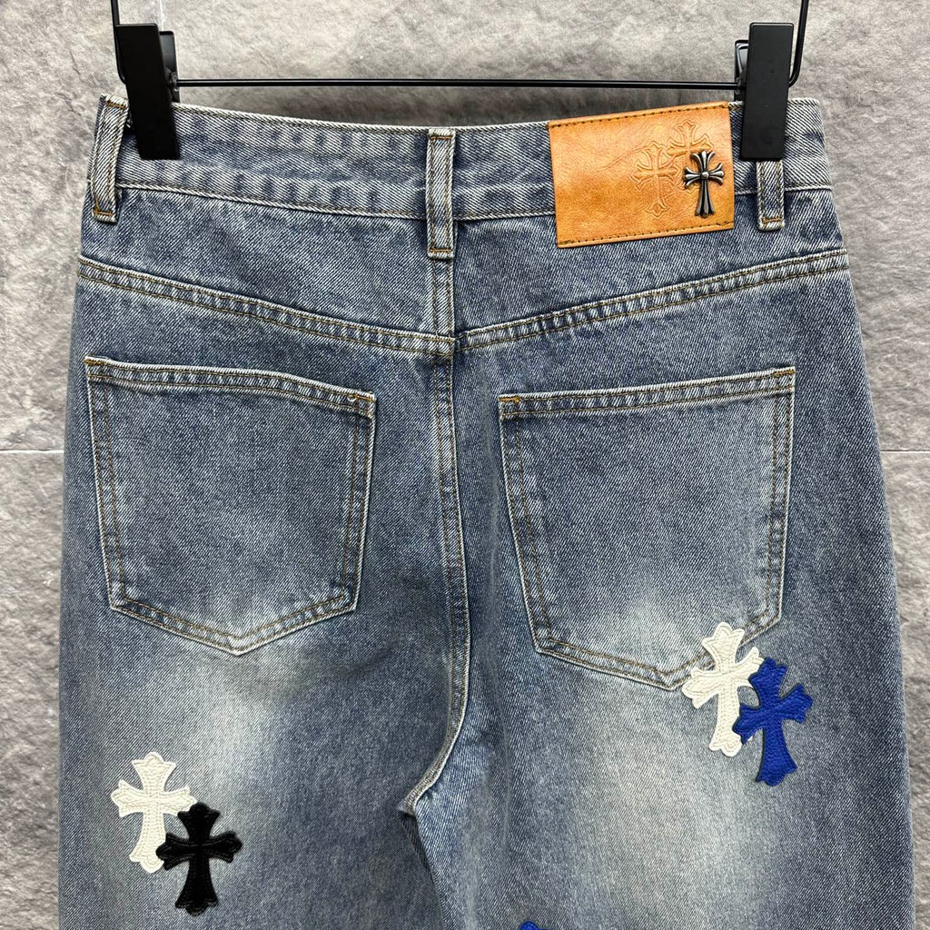 Light-wash denim pants with cross patches and tan logo patch at waistband