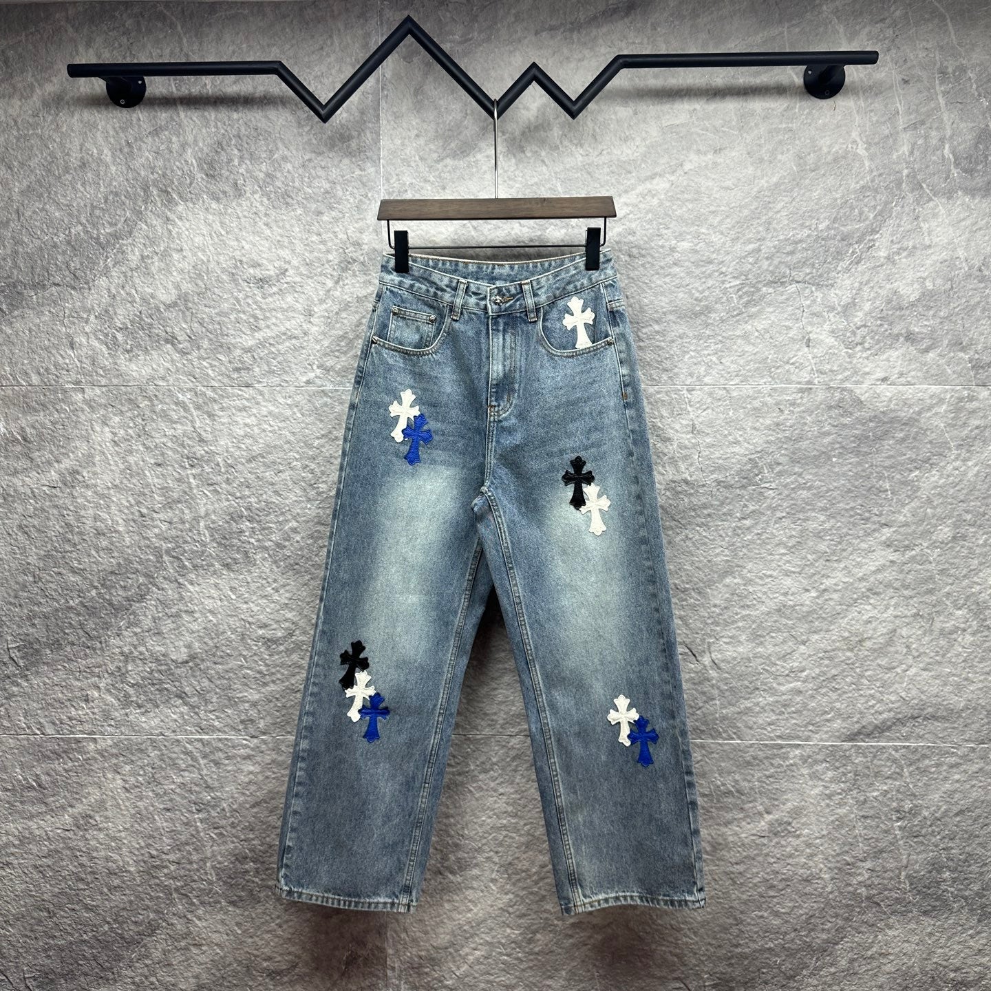 Light-wash denim pants with blue and white cross patches, button fly, straight leg