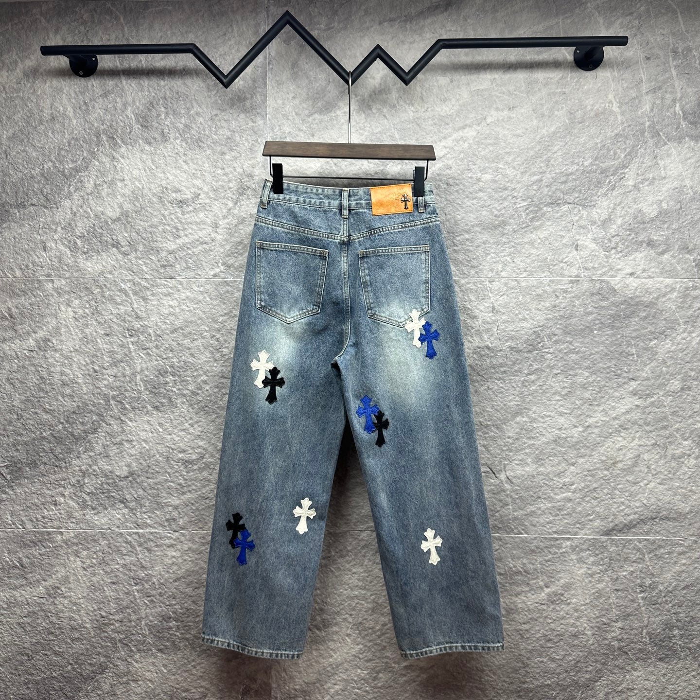 Light-wash denim pants with blue cross patches, back view, wide straight leg
