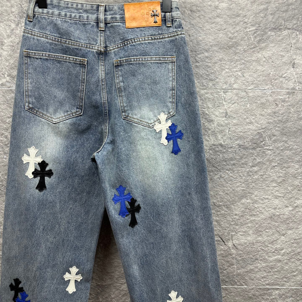 Light-wash denim pants with cross patches on the front legs and tan waistband label