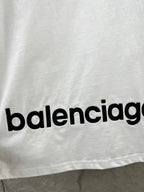Close-up of “balenciag…” text logo on the hem of a white T-shirt.