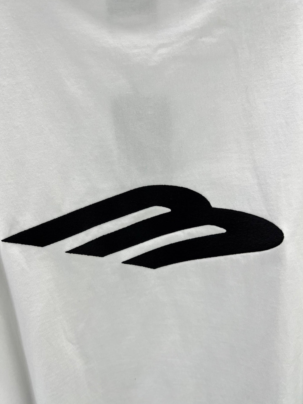 Close-up of large black logo graphic on a white crew-neck T-shirt.