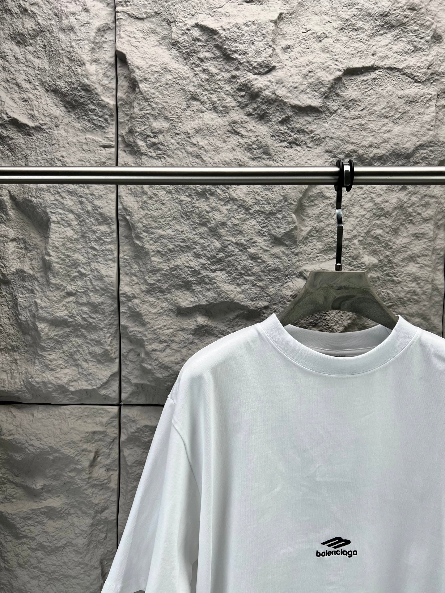 White crew-neck T-shirt with small chest logo and relaxed shoulder fit.