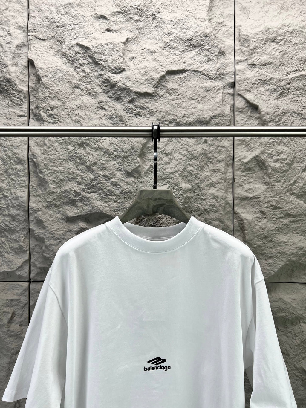White crew-neck T-shirt with small chest logo and wide neckline.