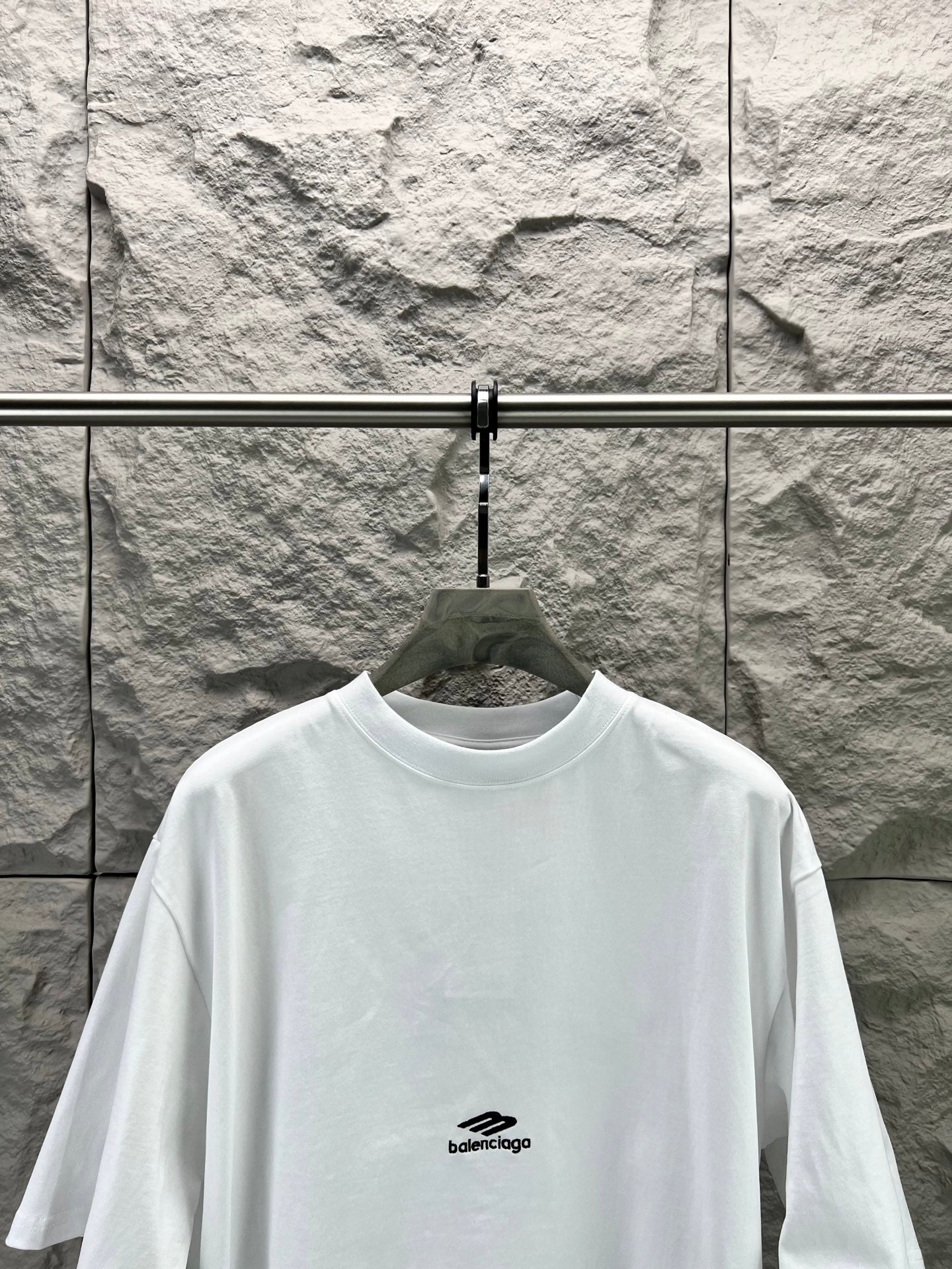 White crew-neck T-shirt with small chest logo and wide neckline.