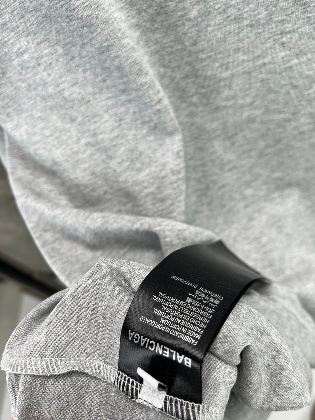 Light blue T-shirt fabric and black brand label tag at stitched hem