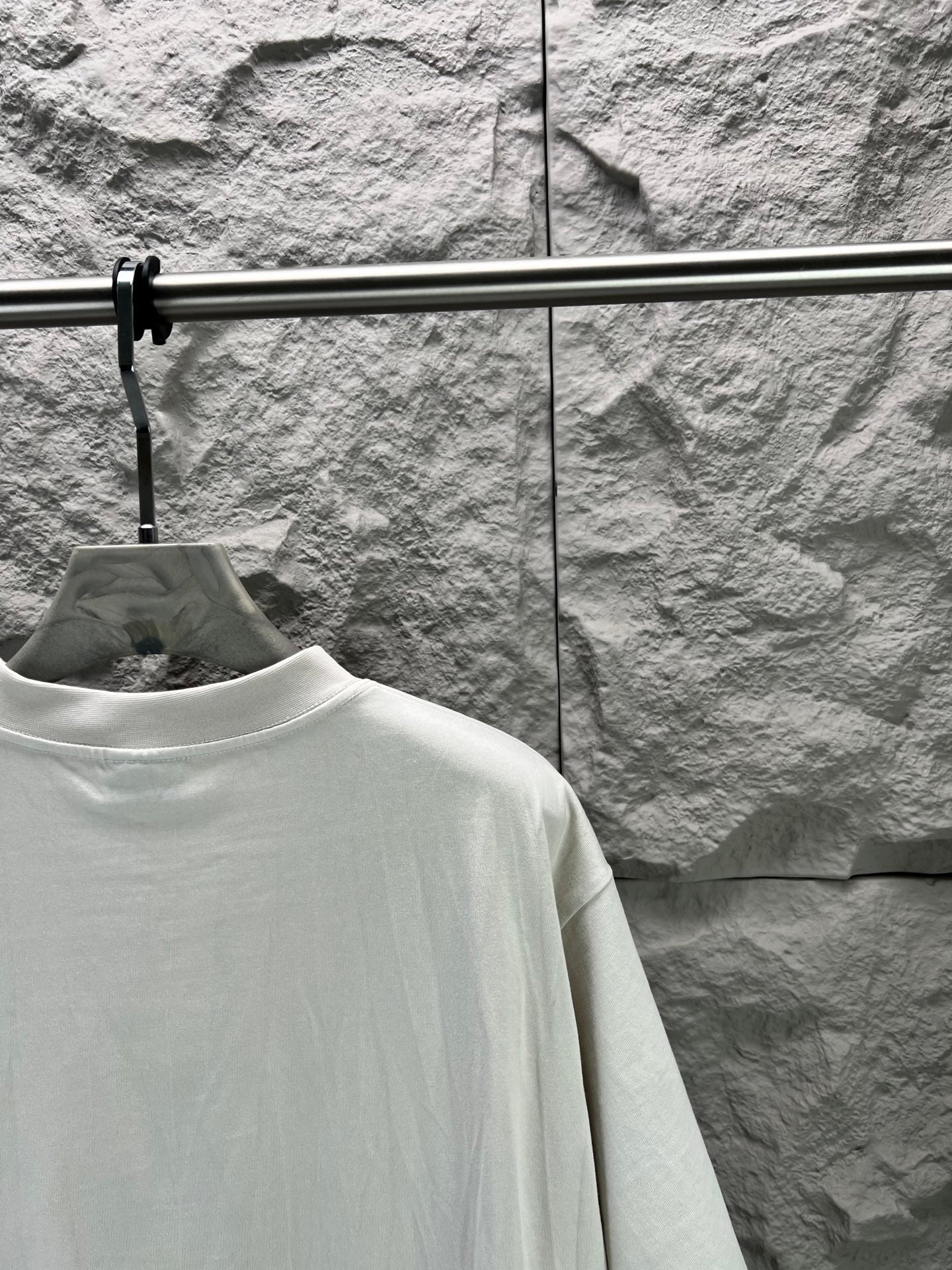Light gray short-sleeve T-shirt back with partial view of sleeve and shoulder