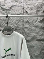 Light gray short-sleeve T-shirt front angled view with green Balenciaga logo