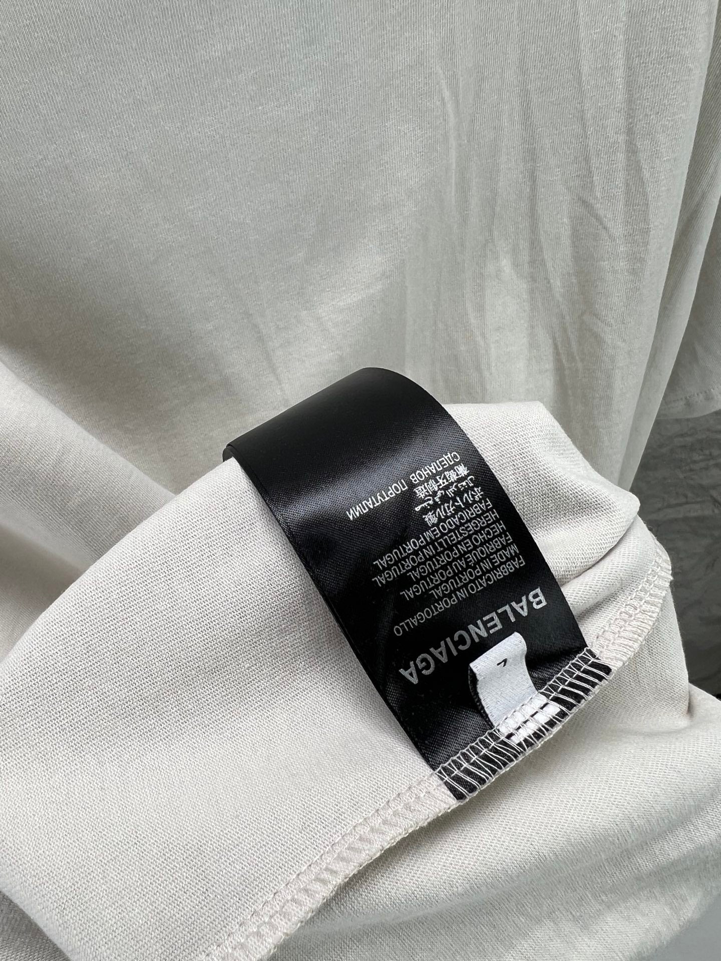 Light gray T-shirt fabric label tag near collar with care text