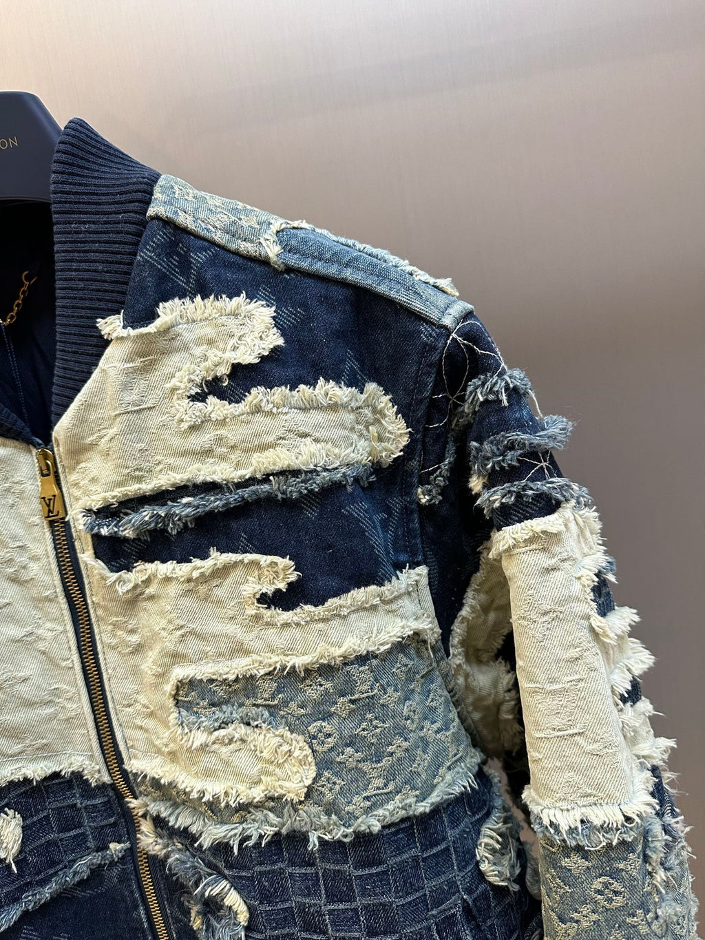 Side view of patchwork denim jacket with zip, blue-and-cream distressed fabric sleeves