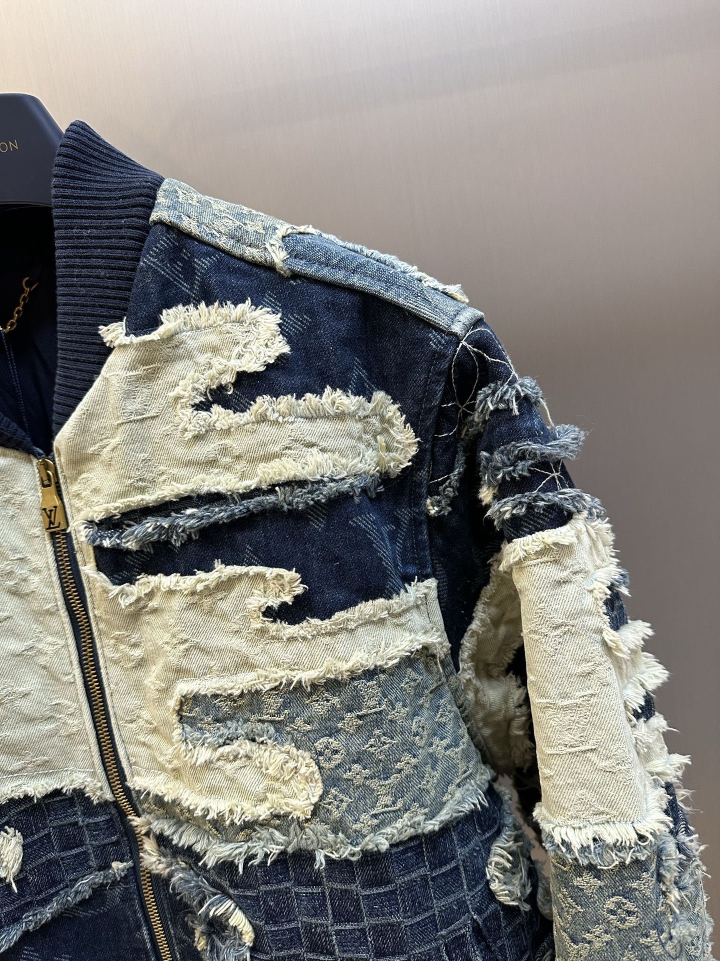 Side view of patchwork denim jacket with zip, blue-and-cream distressed fabric sleeves