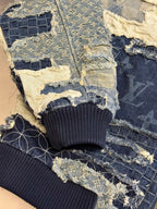 Denim jacket close-up showing ribbed cuffs and patchwork panels with blue-and-cream stitching