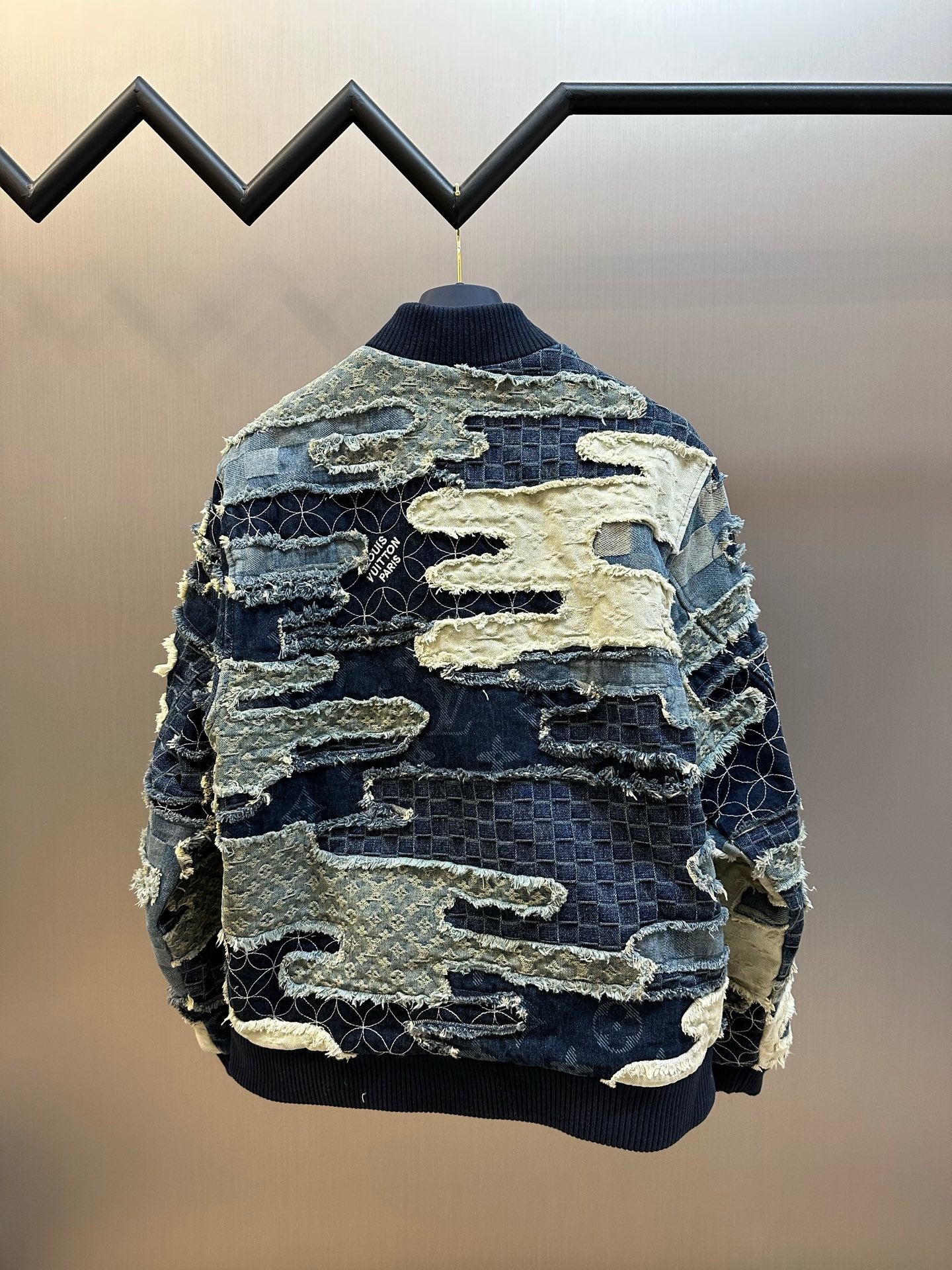 Back view of patchwork denim jacket with ribbed collar and hem, blue and cream panels