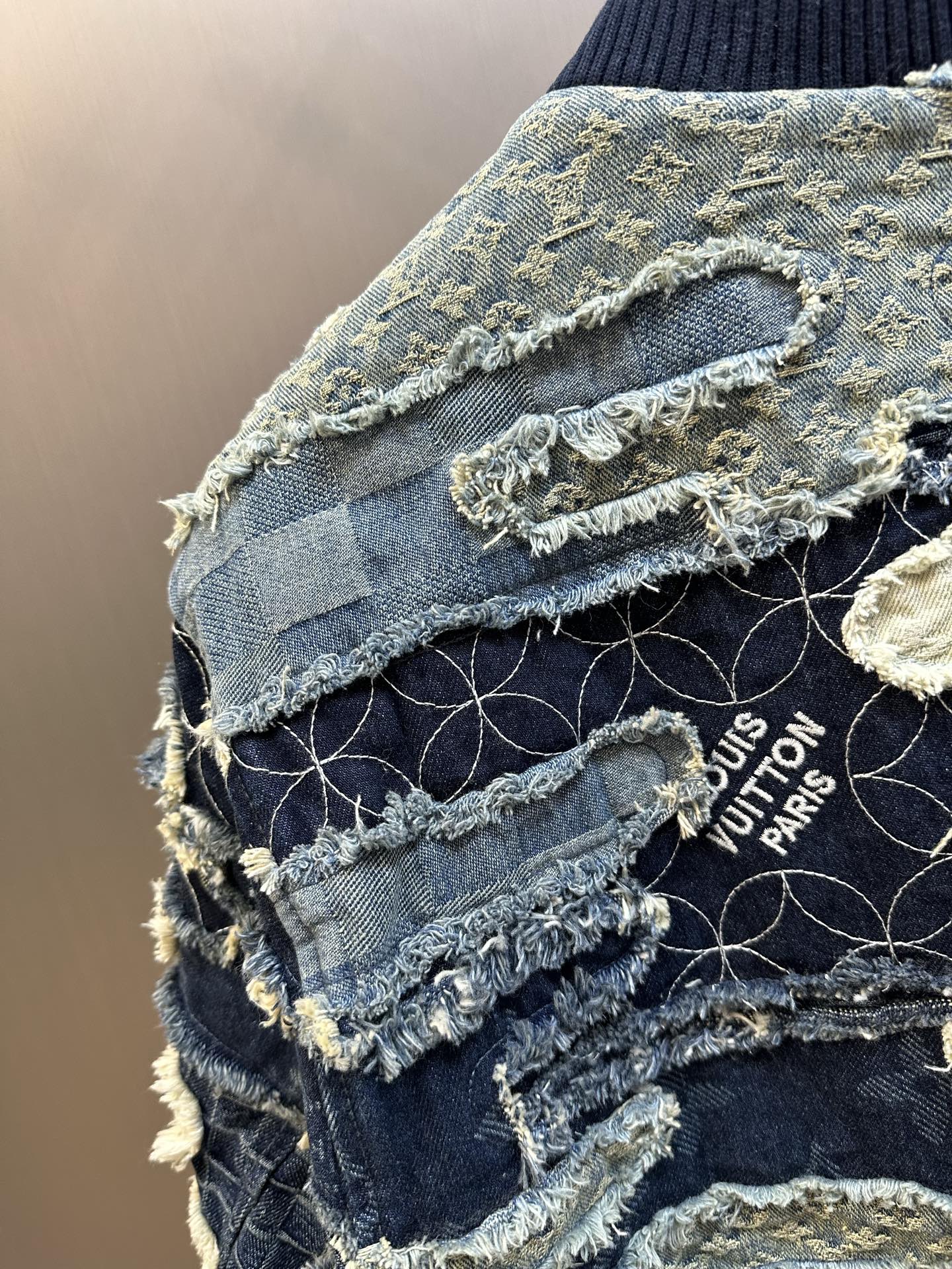 Denim jacket detail with distressed seams and frayed trim, Louis Vuitton Paris patch