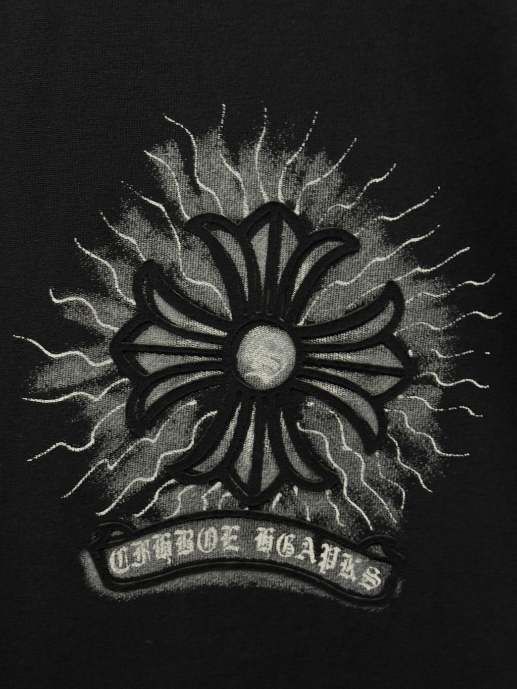 Black T-shirt close-up of large sunburst emblem with lightning rays and halo center