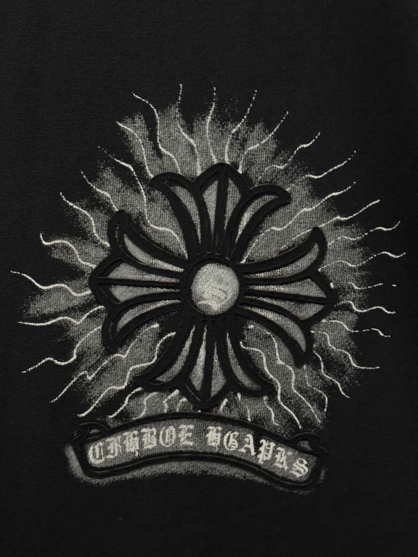 Black T-shirt close-up of large sunburst emblem with lightning rays and halo center