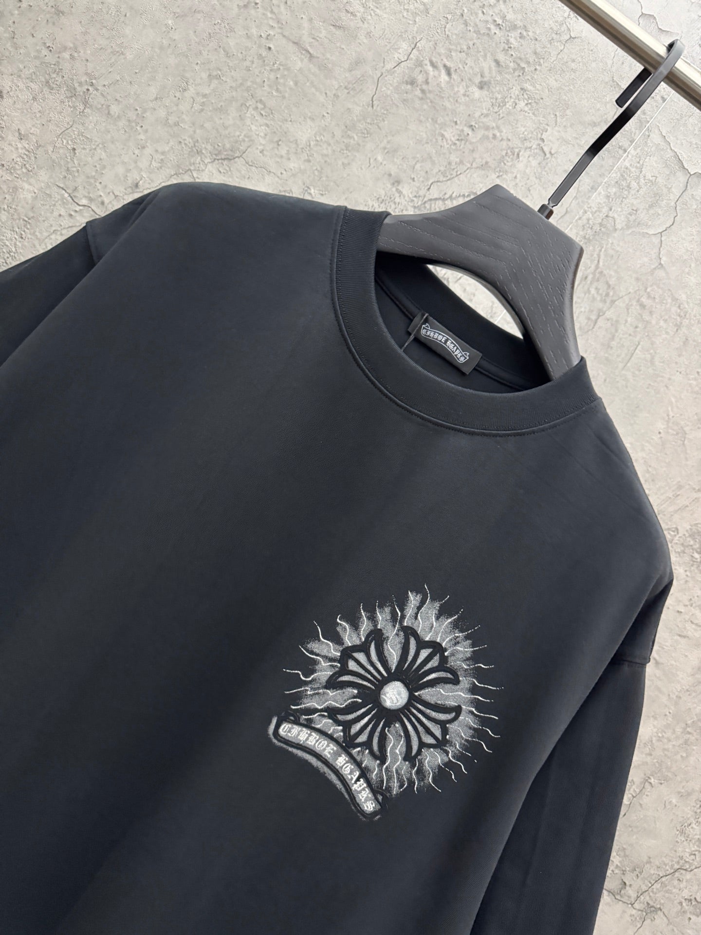 Black crewneck T-shirt with chest sunburst graphic and lightning-style line art