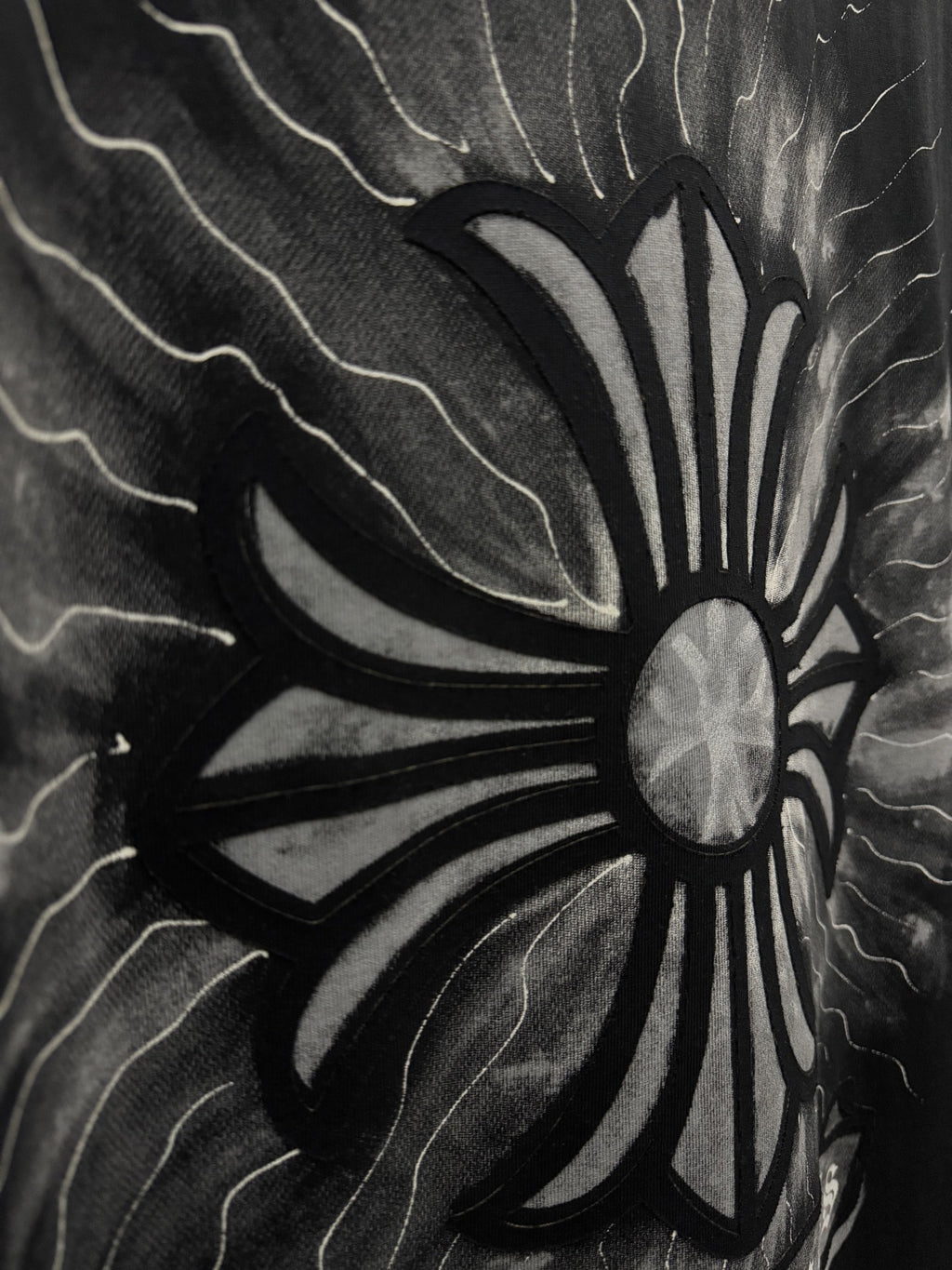 Black T-shirt close-up of stylized sunburst flower graphic with lightning lines