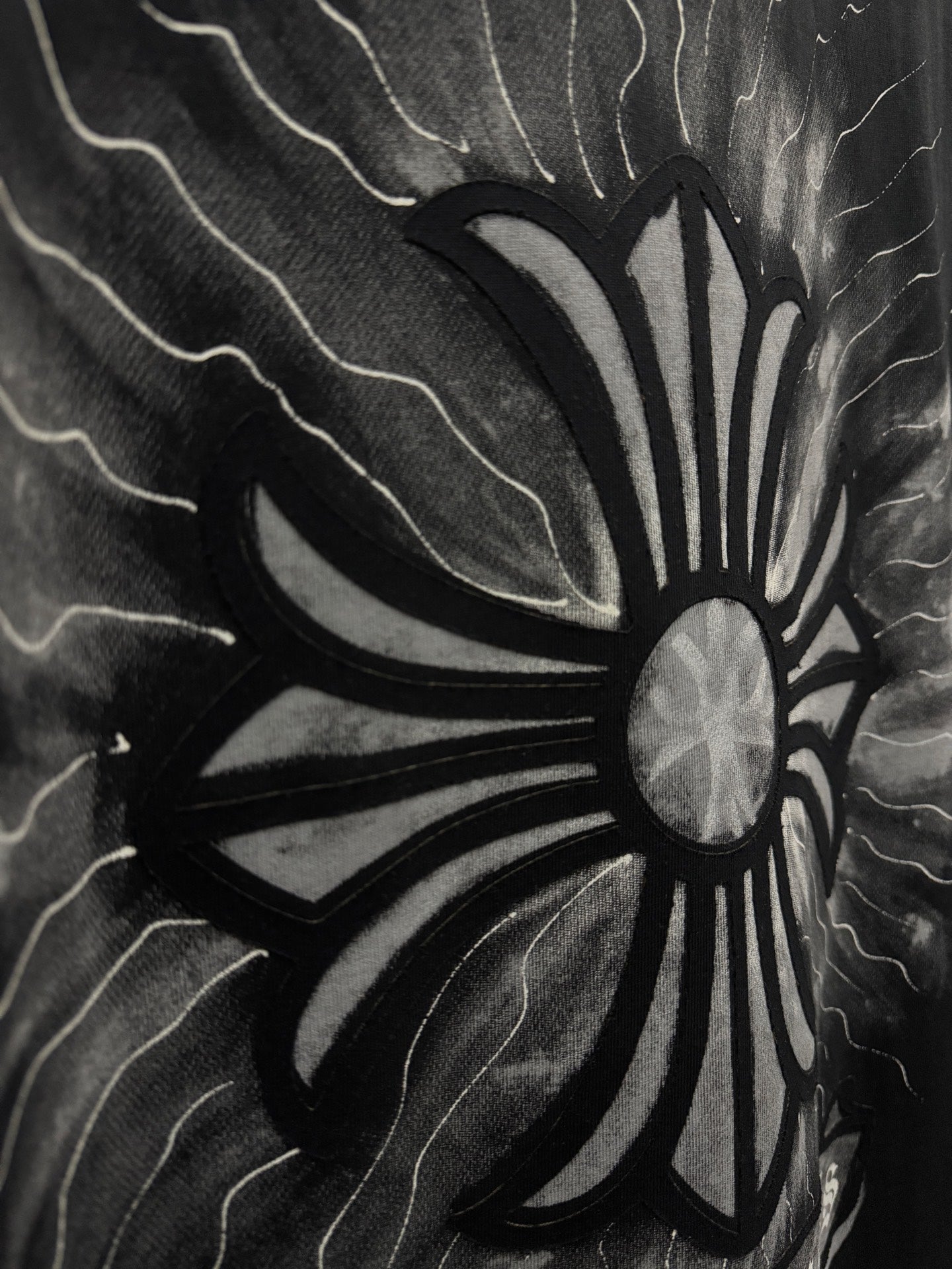 Black T-shirt close-up of stylized sunburst flower graphic with lightning lines