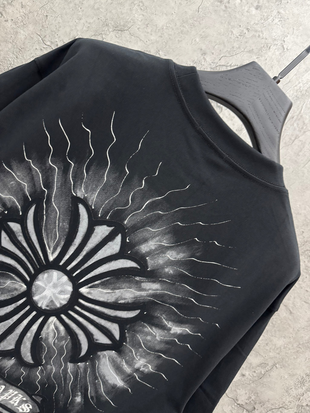 Black T-shirt close-up of back sunburst graphic with lightning line details