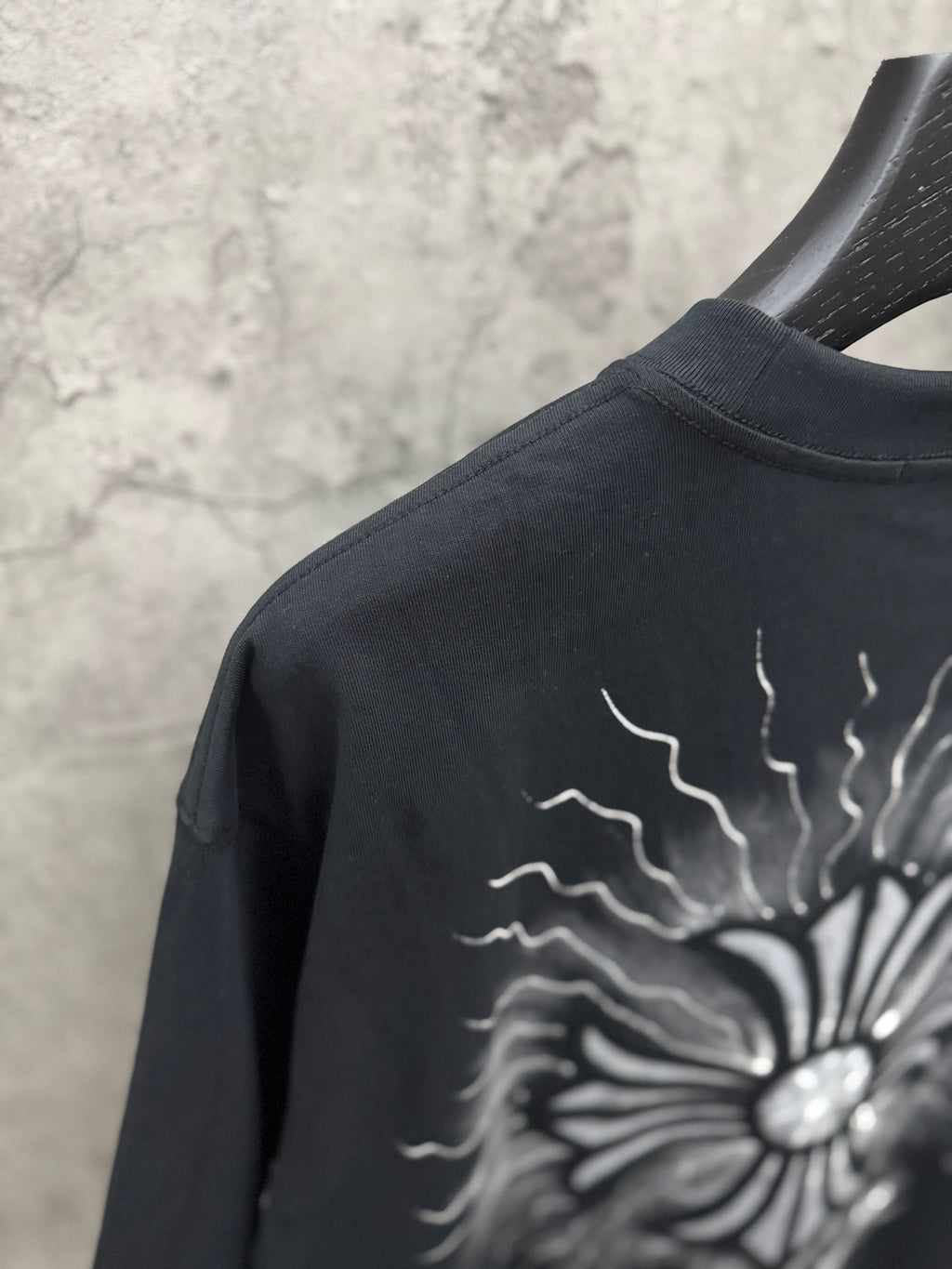 Black T-shirt close-up of back sunburst graphic with lightning-style rays