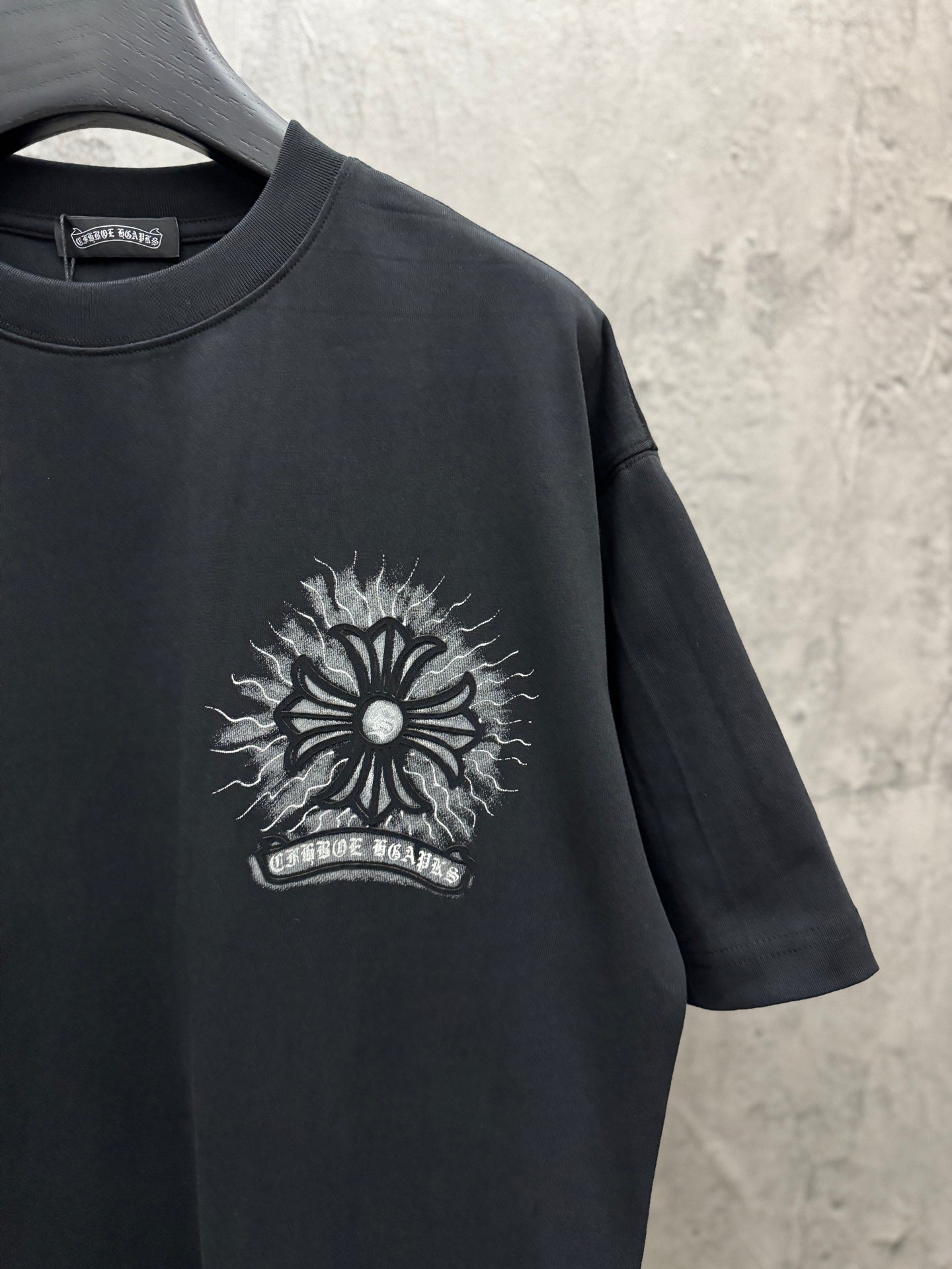 Black short-sleeve T-shirt with chest sunburst logo graphic in light ink