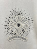 White T-shirt close-up of central sunburst floral emblem with small dark center