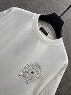 White short-sleeve T-shirt neckline detail with embroidered-style sunburst floral logo