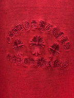 Red T-shirt fabric close-up showing embossed crest and decorative rhinestones